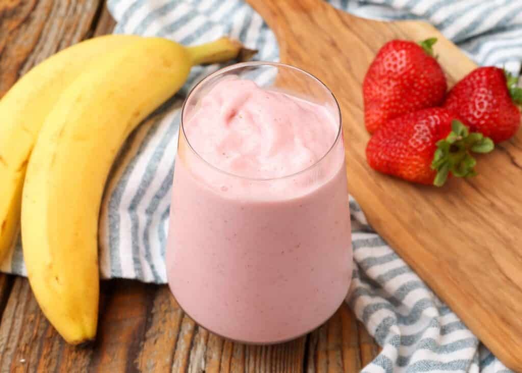 Strawberry smoothie with bananas and berries on board with striped blue towel