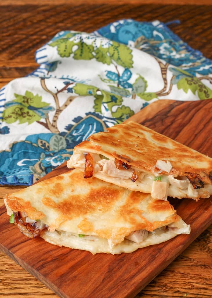 A vertically aligned photo of two quesadilla halves on a wooden serving board. - 7