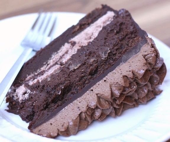 A piece of chocolate cake on a plate, with Ganache