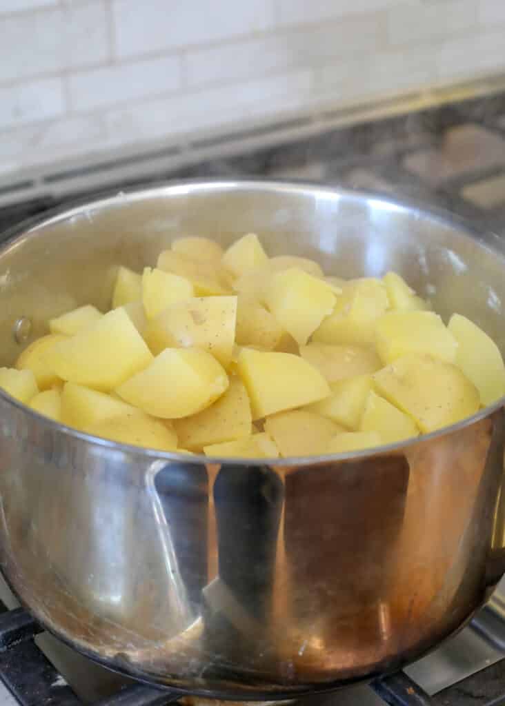 Place the drained potatoes back over low heat to release the steam while mashing them.
