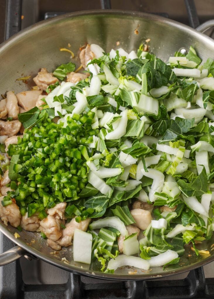 Saltee los ingredientes del pollo Bok Choy en una sartén para saltear