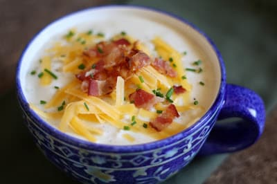 A bowl of food on a plate, with Soup and Potato