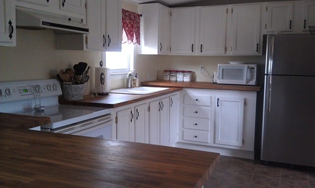 A kitchen with white cabinets and stainless steel appliances and wooden cabinets