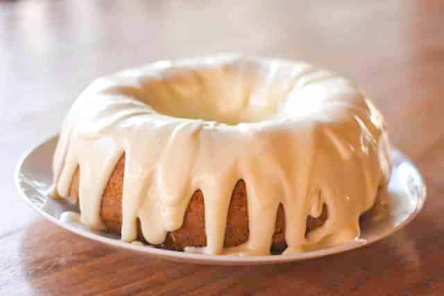 carrot bundt cake on plate covered with cream cheese frosting 