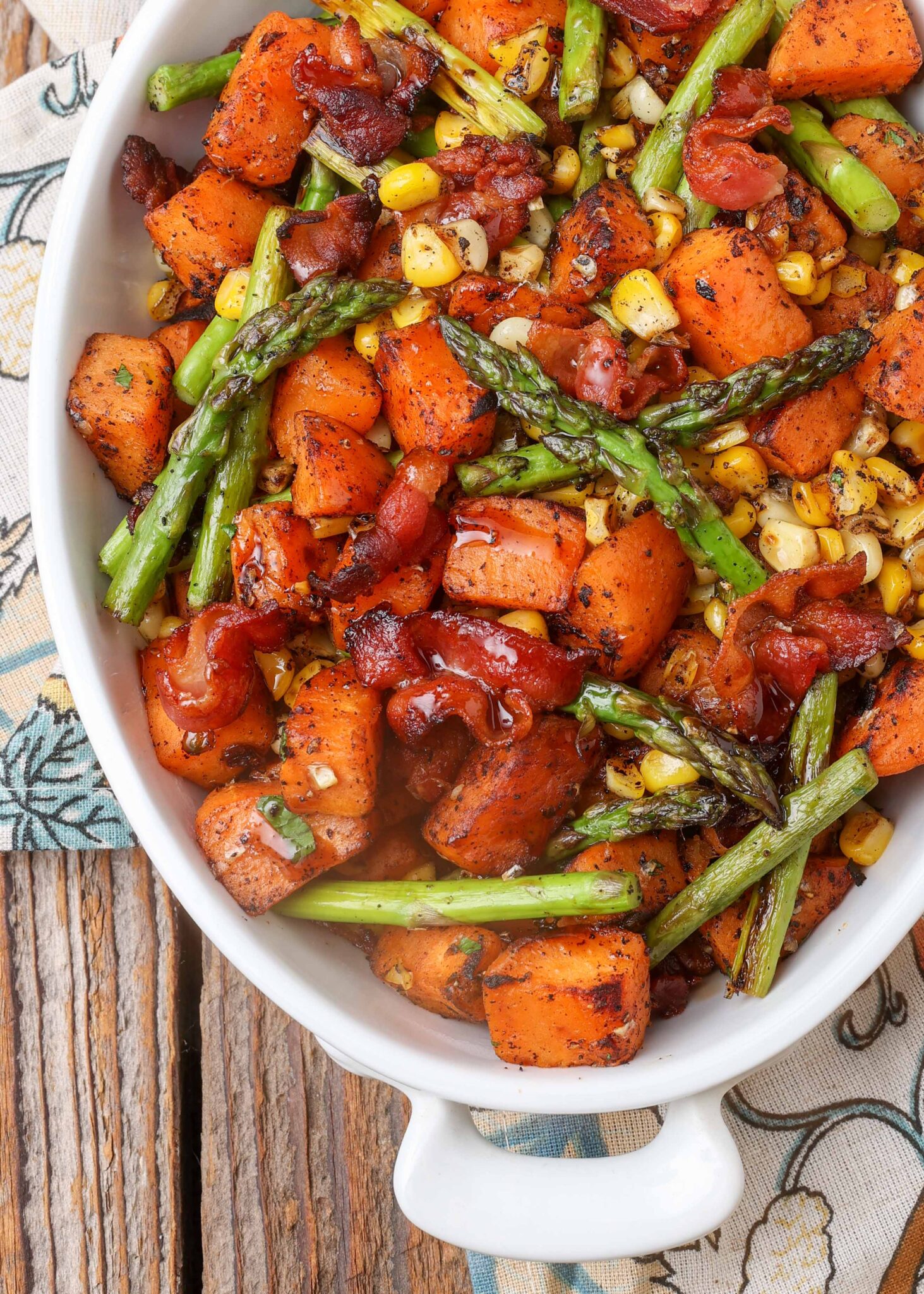 sweet potatoes, asparagus, corn, and bacon in oven white dish