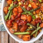 sweet potatoes, asparagus, corn, and bacon in oven white dish