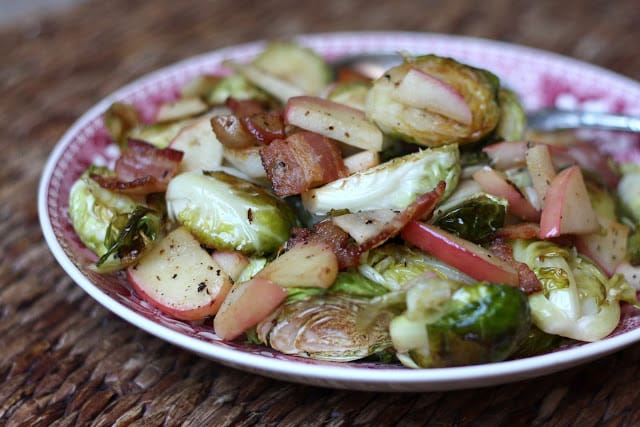 A plate of food on a table, with Bacon and Brussels sprout