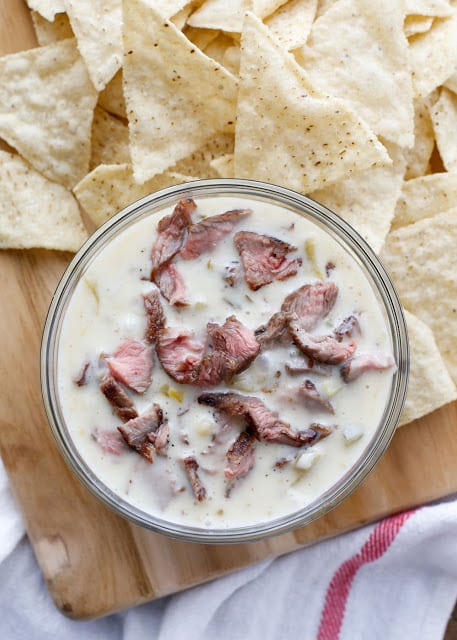 Creamy, spicy, cheesy Steak Queso Dip is a hearty appetizer that everyone loves! Get the recipe at barefeetinthekitchen.com