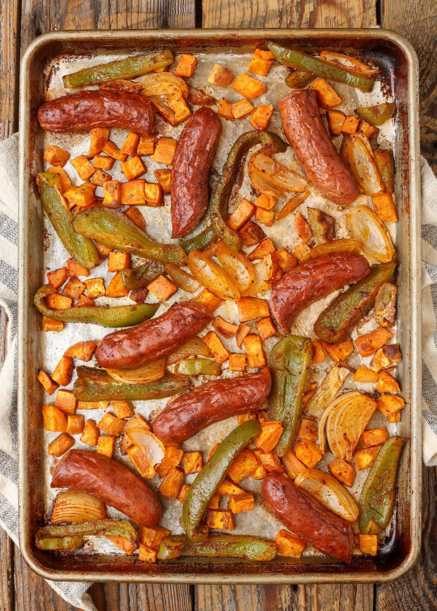 peppers, onions, and sausage on sheet pan with towel