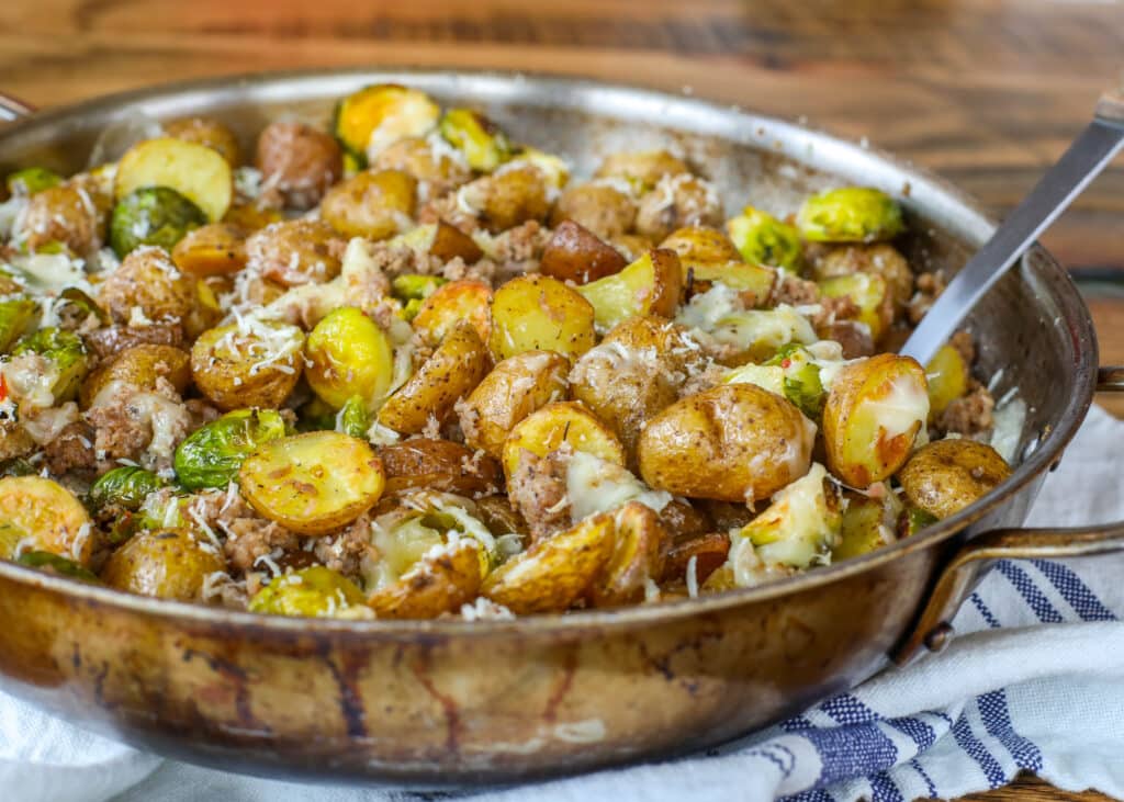 Cheesy Roasted Potatoes with Crisp Brussels Sprouts and Spicy Sausage is a dinner that everyone devours!