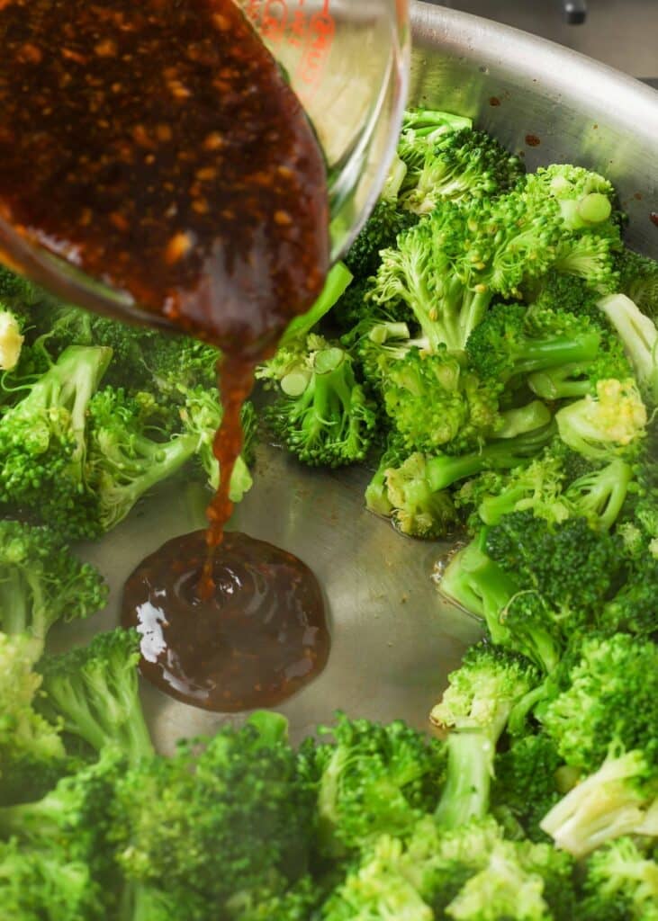 stir fry sauce poured into pan with broccoli