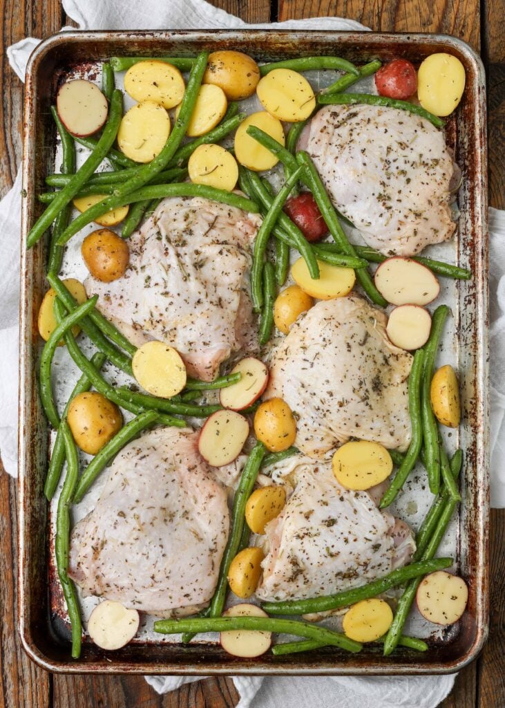 chicken thighs with green beans and potatoes on large metal sheet pan