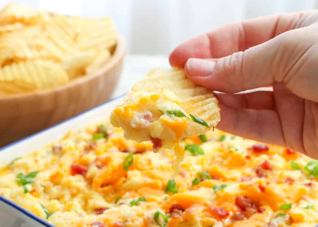 Twice Baked Potato Dip scooped onto a potato chip is a game day favorite! get the recipe at barefeetinthekitchen.com