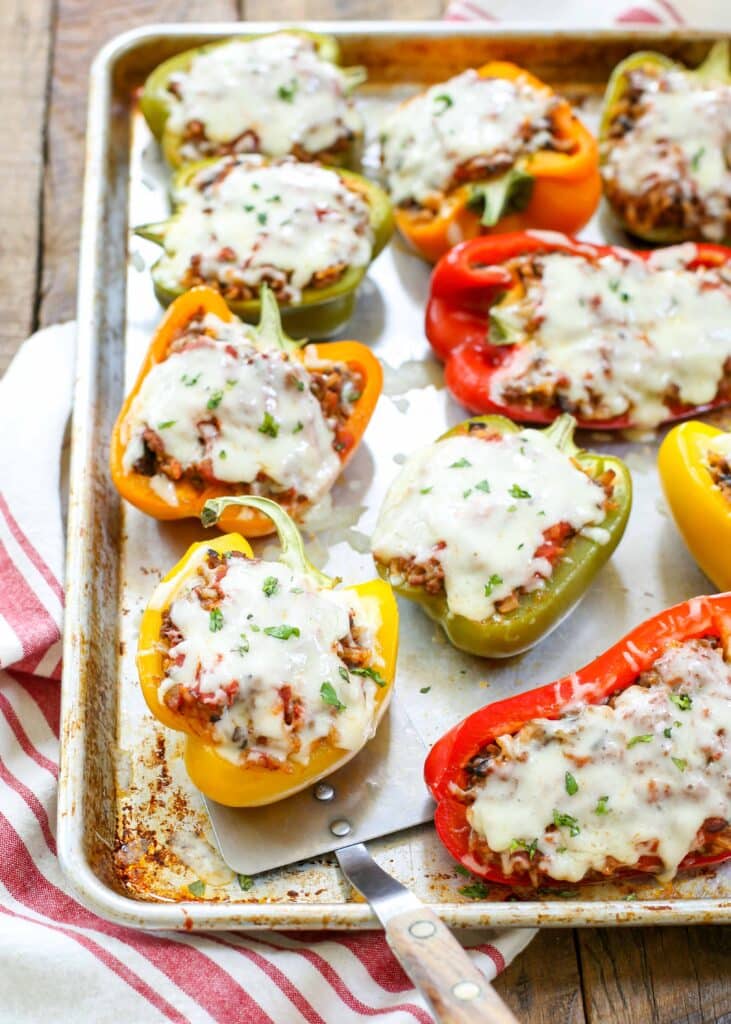 ground beef and rice stuffed peppers with cheese on baking sheet
