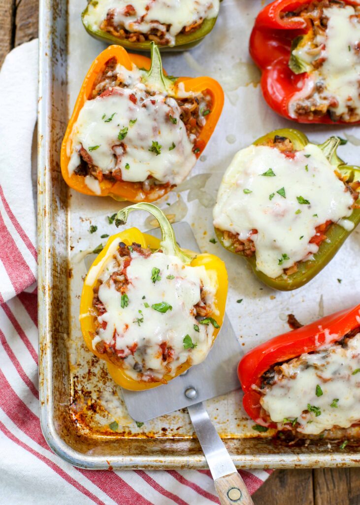 Italian style peppers stuffed with cheese and beef on a tray with a spatula