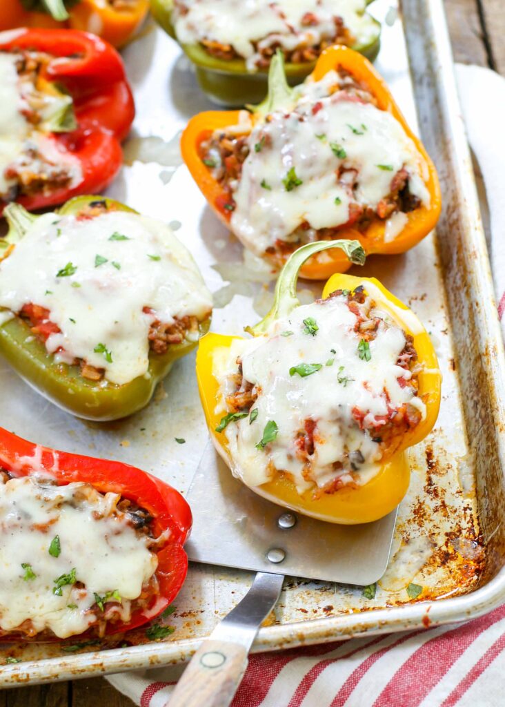 Italian style stuffed peppers on metal tray with striped towel