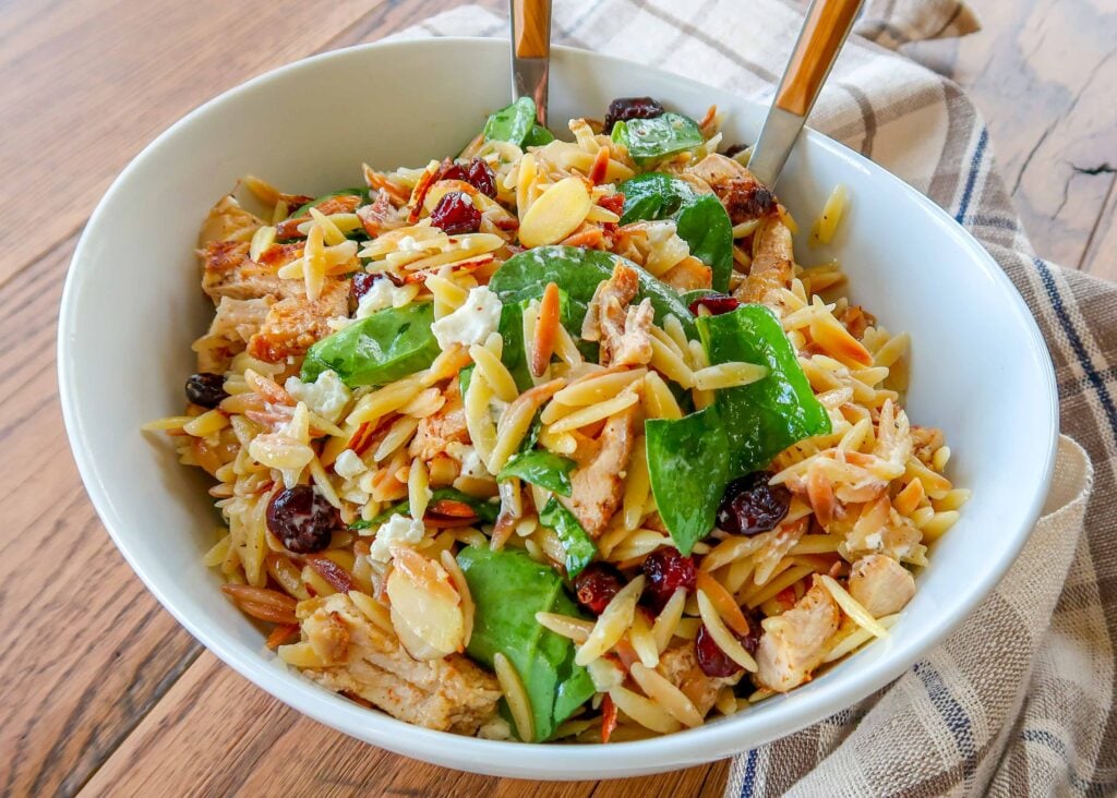 Spinach Orzo Salad with Cranberries, Almonds, and Goat Cheese in mixing bowl