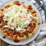 Cornbread Waffles piled high with pulled pork and coleslaw on a plate - get the recipe at barefeetinthekitchen.com