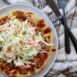 Cornbread Waffles topped with pulled pork and coleslaw on a plate. Get the recipe at barefeetinthekitchen.com