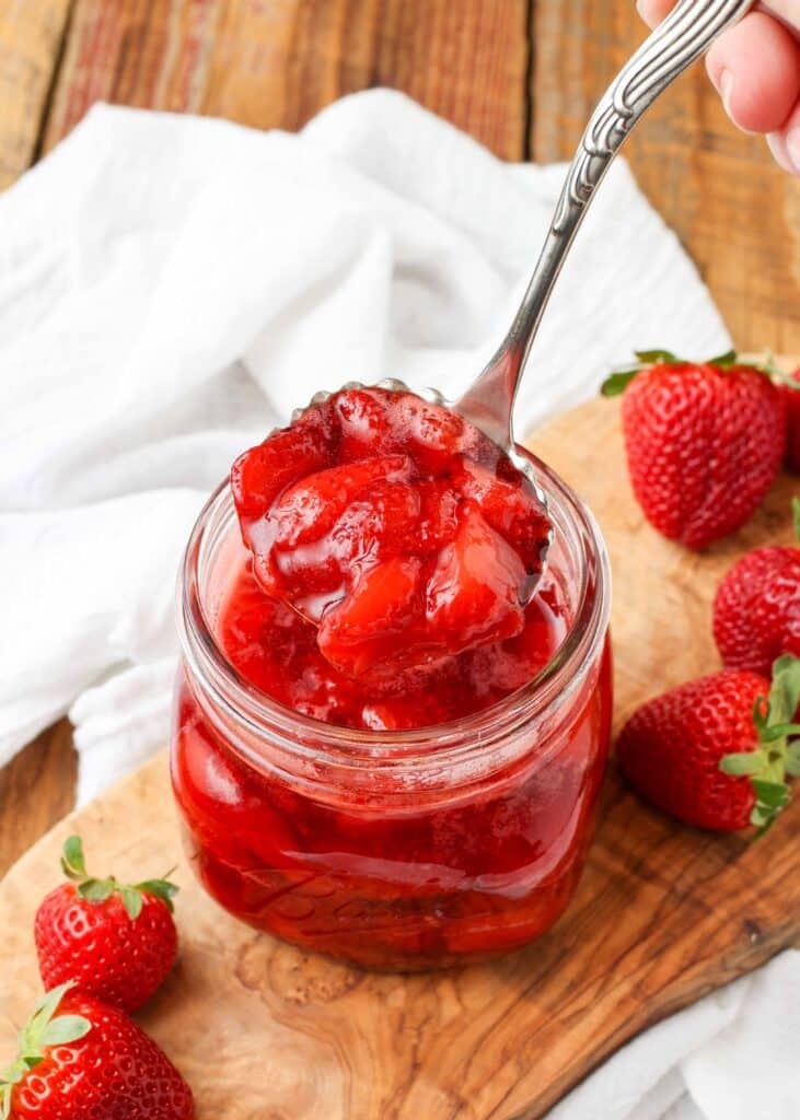 Strawberry compote in a ladle over a jar