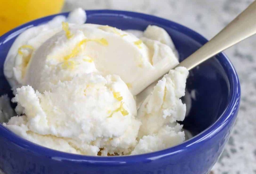 Close up photo of ice cream in blue bowl with gold spoon.