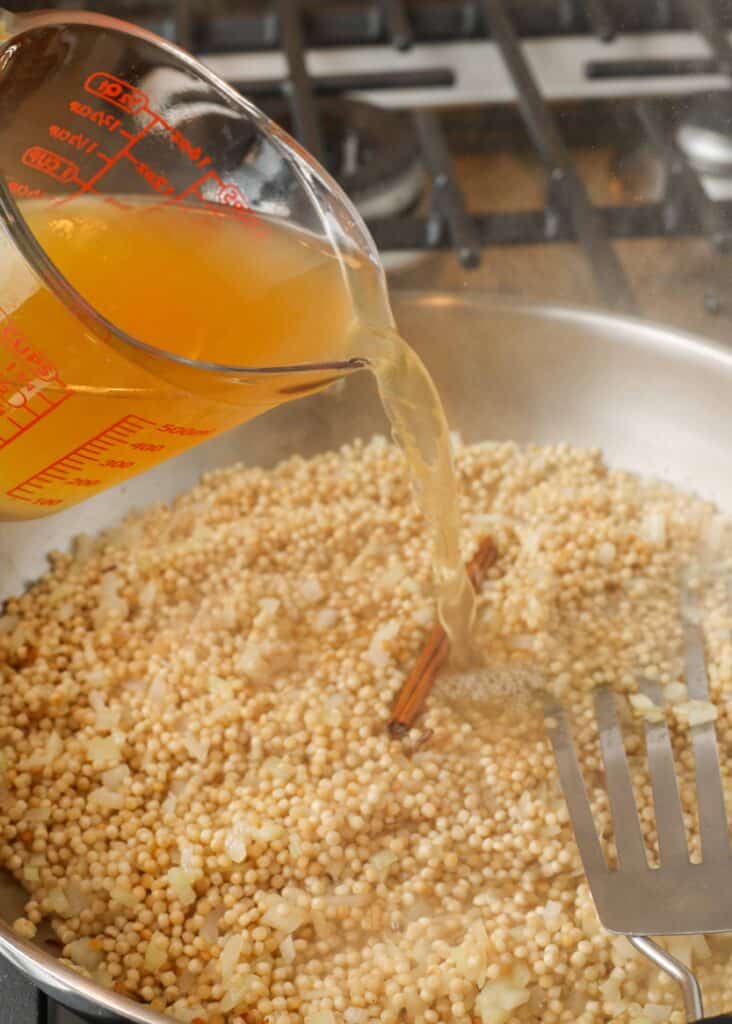 israeli couscous in large skillet with broth