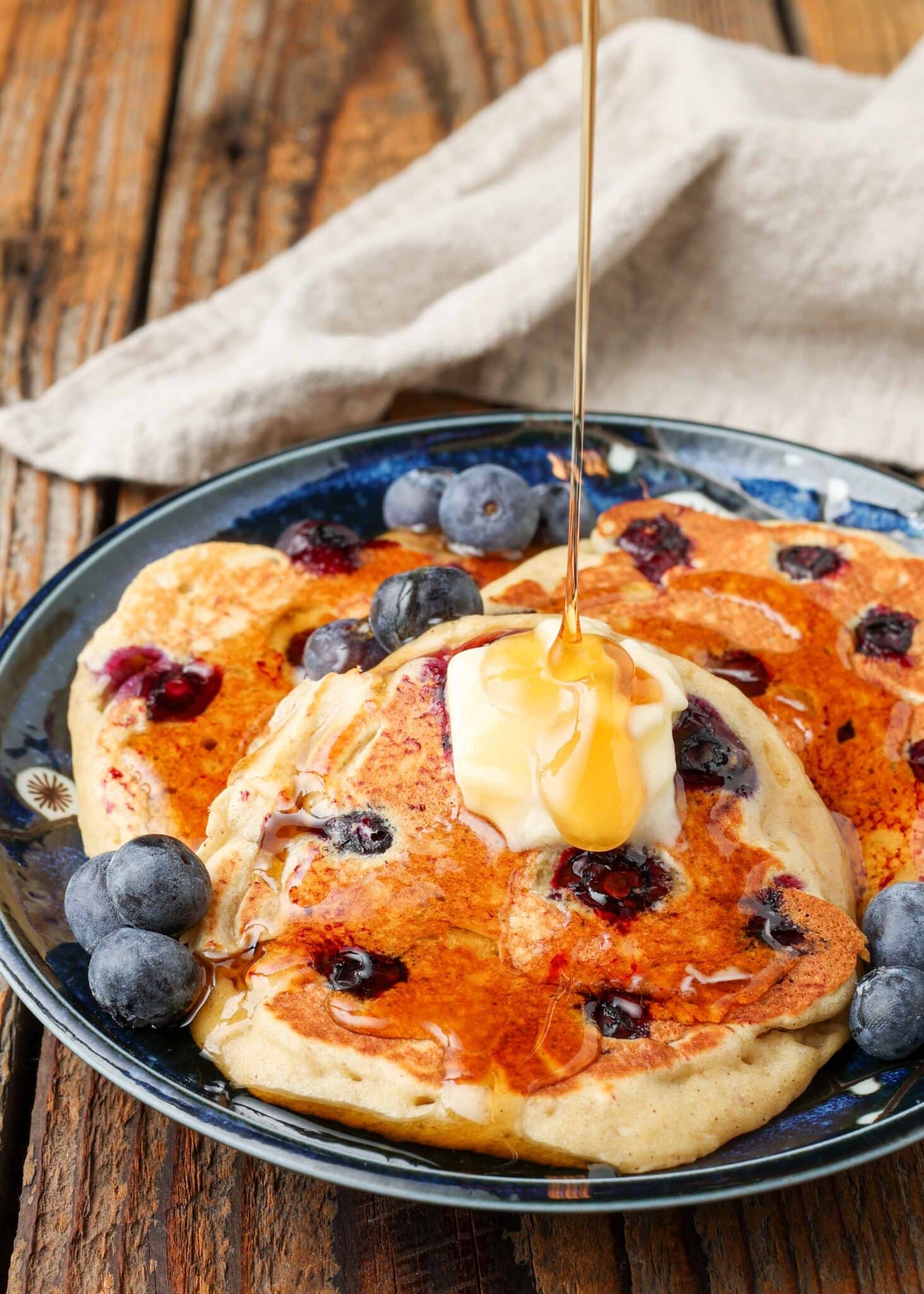 banana pancakes with blueberries on plate with butter and syrup