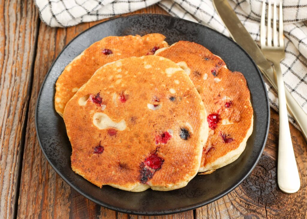 Cranberry Pancakes on black plate with gold fork