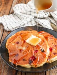 syrup poured over butter on cranberry pancakes