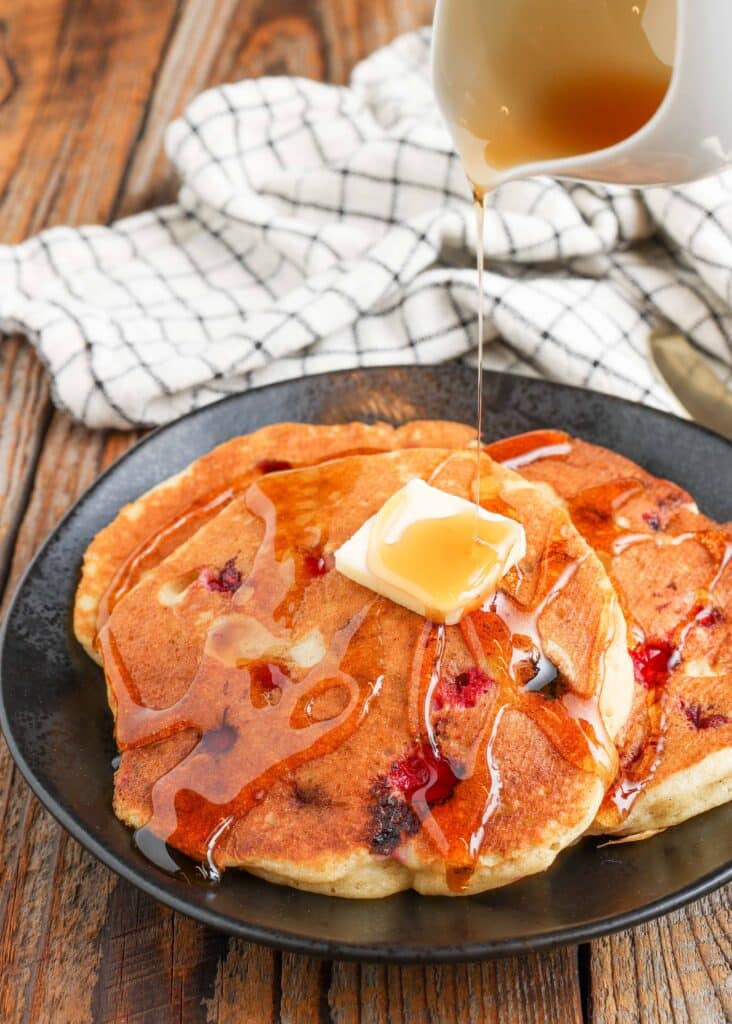 syrup poured over butter on cranberry pancakes