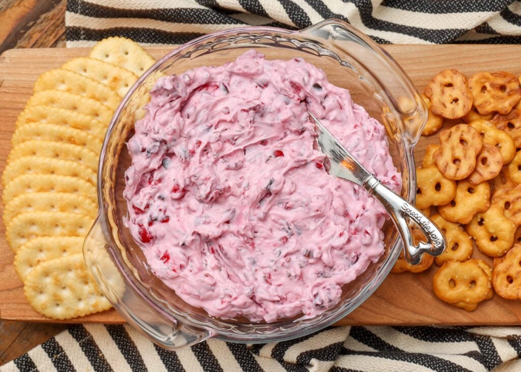creamy cranberry dip in shallow bowl on cutting board with crackers