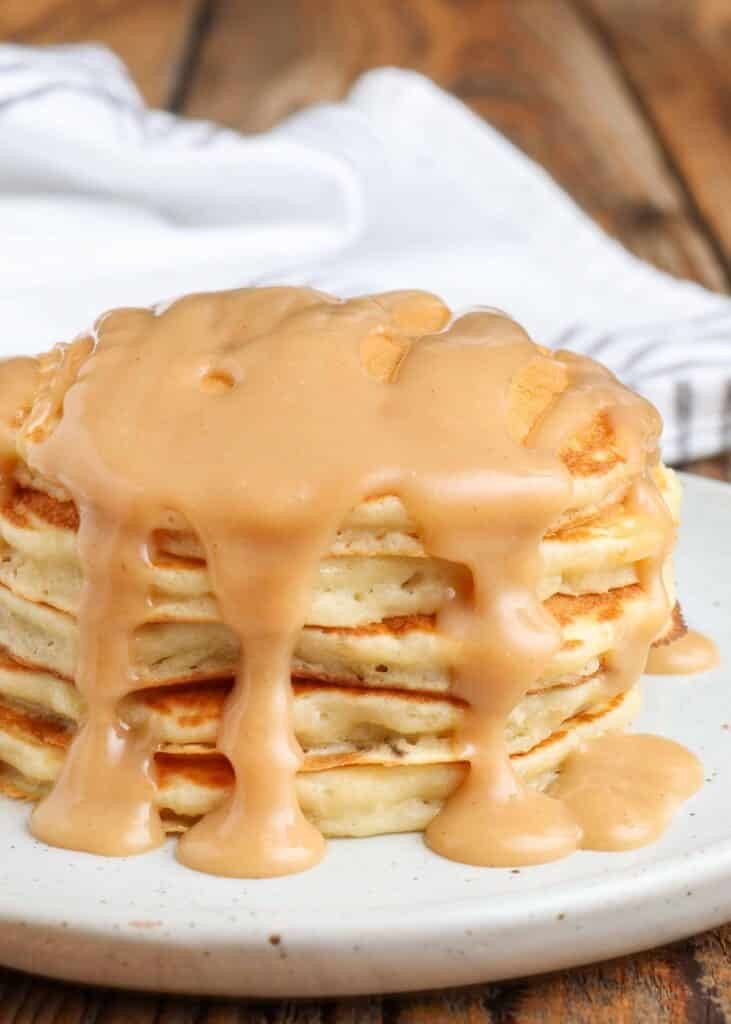 Close-up pouring syrup over pancakes stacked on plate