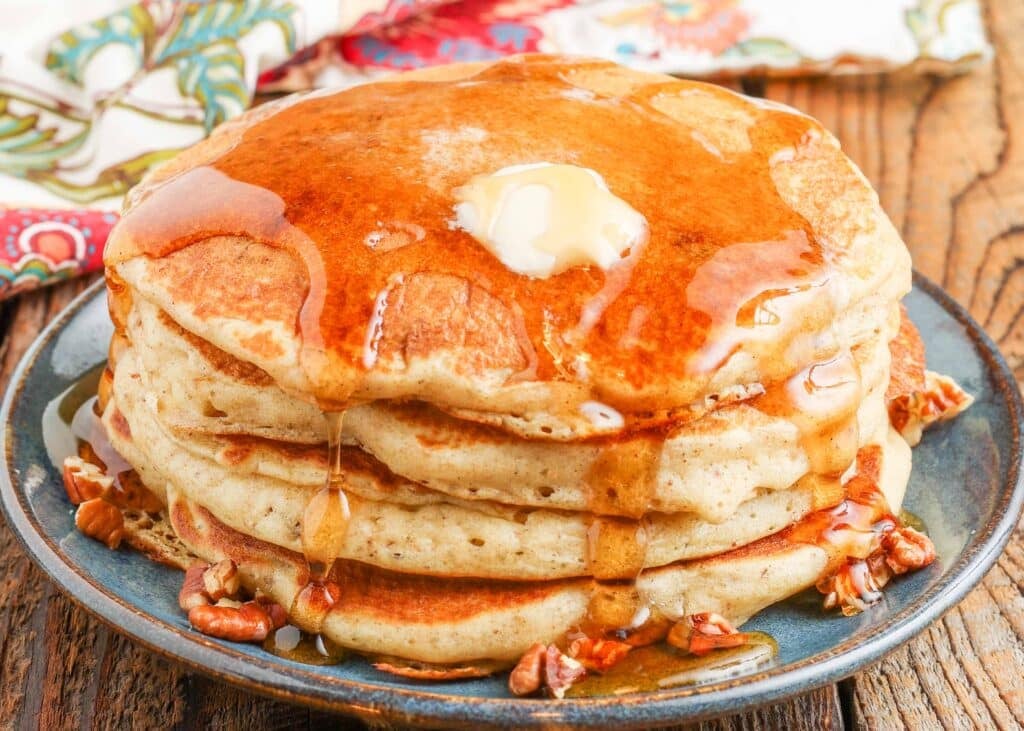 syrup over pancakes stacked on blue plate