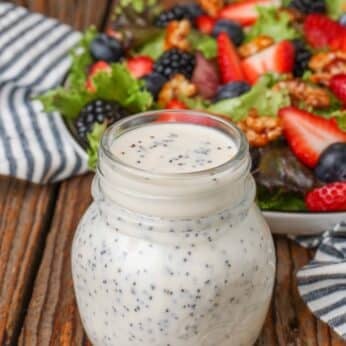 poppy seed dressing in jar next to salad with berries