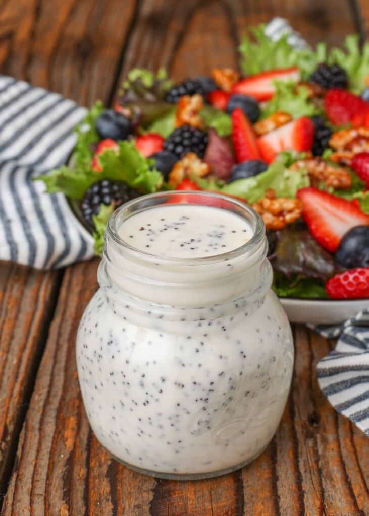 poppy seed dressing in jar next to salad with berries