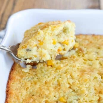 corn pudding with jalapenos in a white baking dish with serving spoon