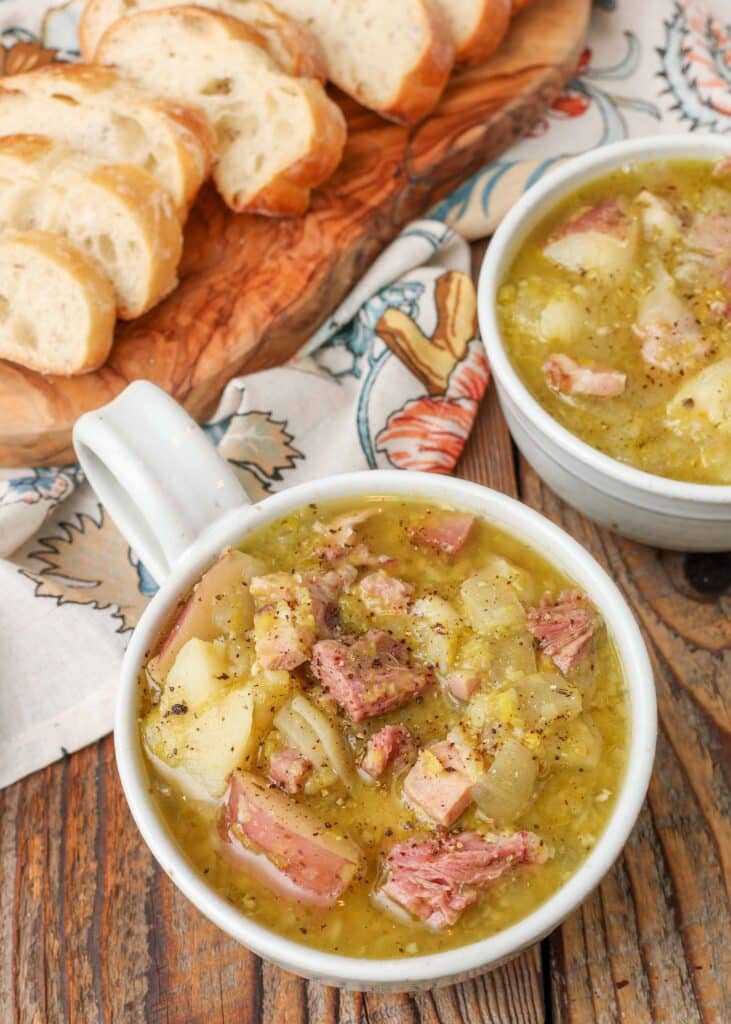 Ham and potatoes in split peas soup in white bowls with bread