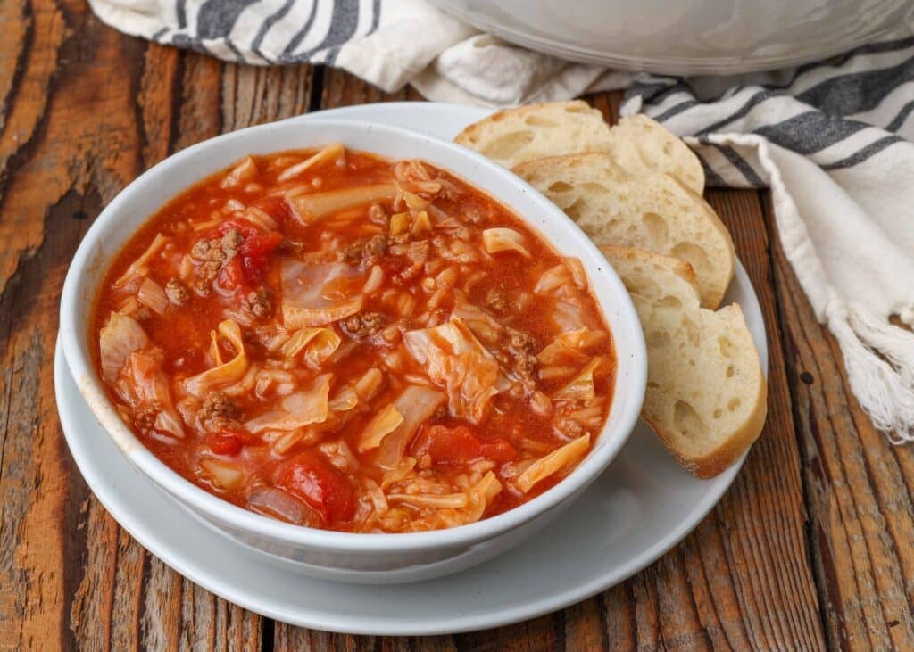 Cabbage Roll Soup in white pottery with bread slices