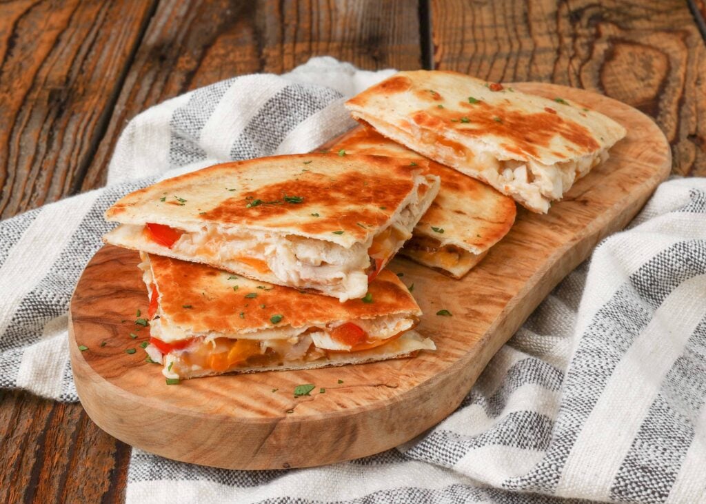 quesadillas stacked on wooden board with striped towel
