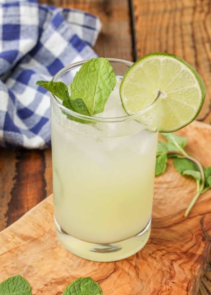 cocktail ghiacciato con menta e lime accanto al tovagliolo blu e bianco