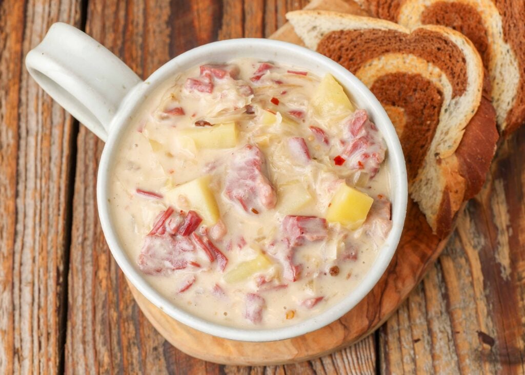 creamy Reuben soup in a pottery mug with rye toast