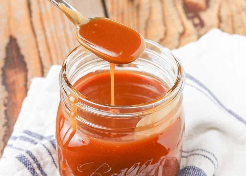 caramel sauce in short jar with spoon