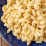 close up photo of cheesy macaroni in blue bowl