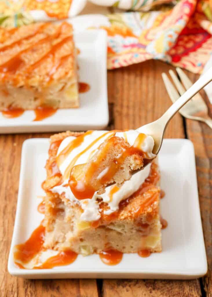 Apple Cake with Caramel Sauce square piece on white plate with cream and fork