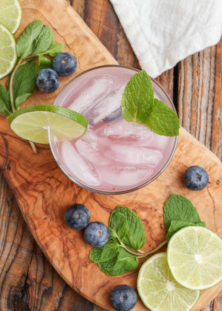 ice cubes are visible in this pink cocktail with blueberries, mint, lime juice, and rum.