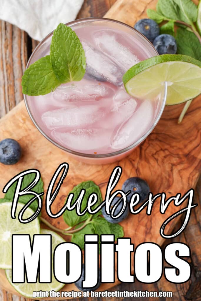 a top down photo of a glass containing a lovely pink colored blueberry mojito, garnished with mint leaves. the image is overlaid with white lettering that reads: "Blueberry MOJITOS"