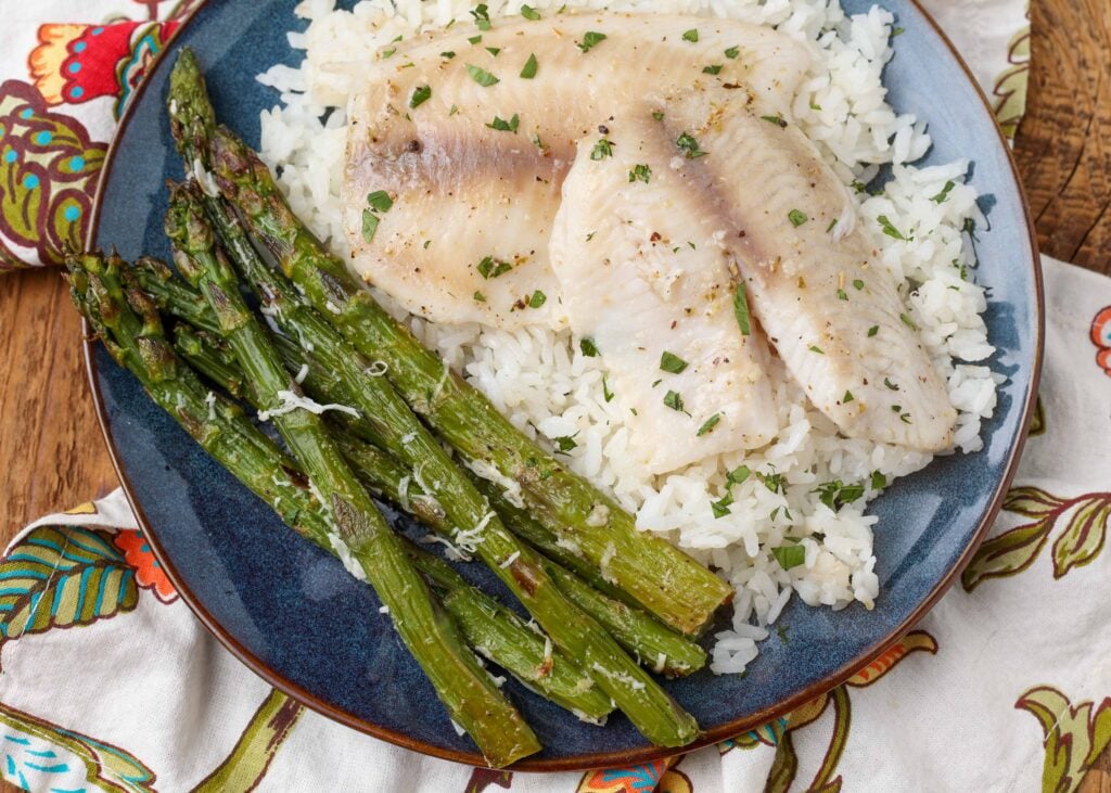 Tilapia with rice and asparagus on a blue plate