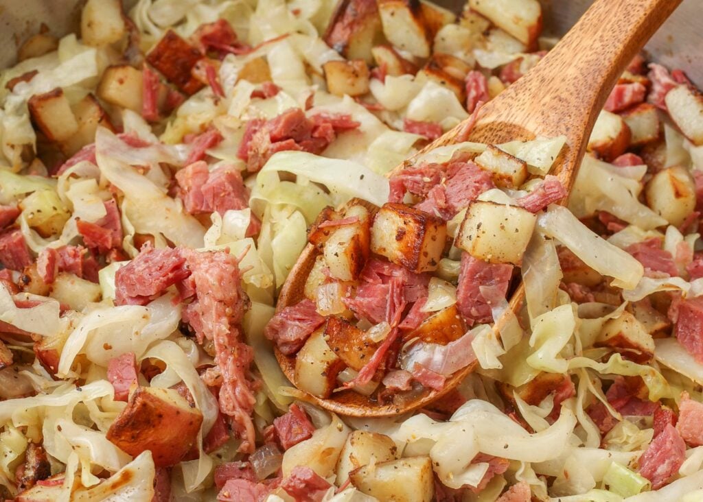 Hash di cavolo di carne in scatola con patate in un cucchiaio di legno