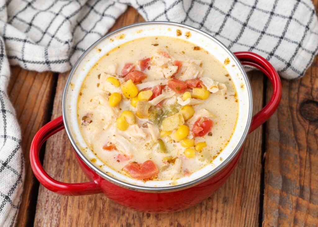 foto ravvicinate di zuppa di pollo e mais in coccio rosso con tovagliolo