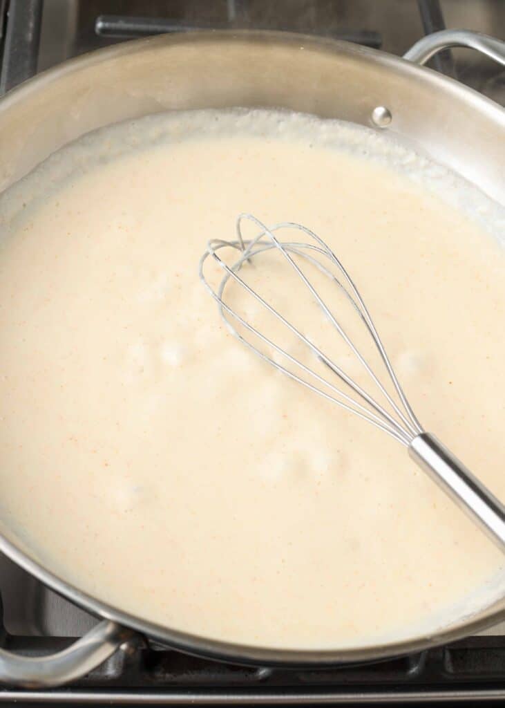 a whisk rests in the metal pan with a cream and spice mixture fully combined